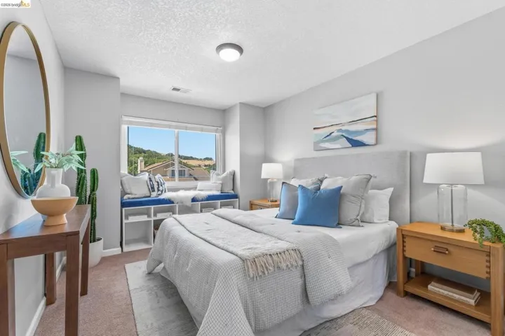 Bedroom featuring a window seat with built-in shelving, a large picture window, textured carpeting, and a flush mount ceiling light