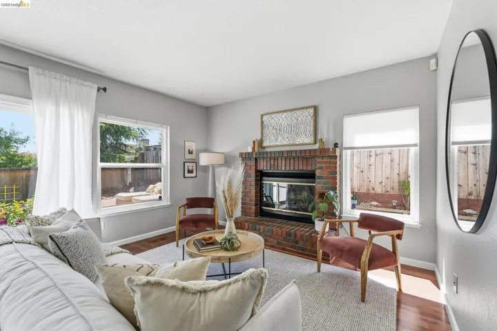 Living area featuring a brick fireplace, rich wood-finish flooring, and multiple windows