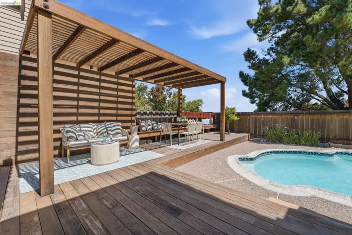 Outdoor living space featuring a wood pergola with slatted roof and privacy wall