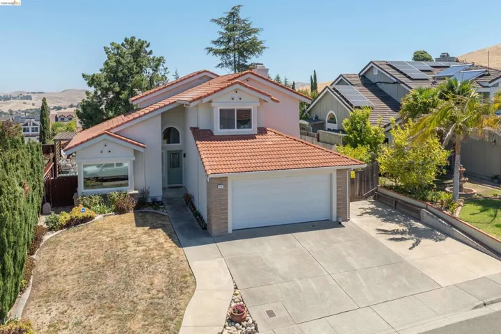 Contemporary stucco exterior with a terra cotta tile roof, an arched entry, a two-car garage, and a concrete driveway