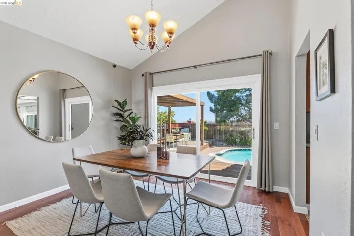 Dining area with vaulted ceiling and wood-finish flooring