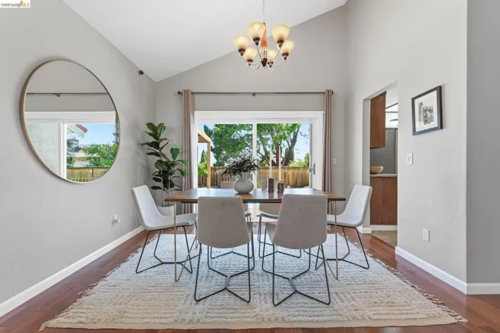 Vaulted ceiling dining area featuring wood-finish flooring and a sliding glass door