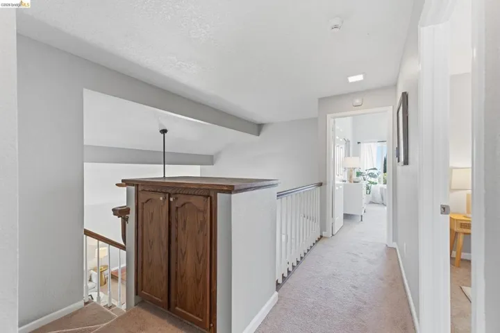 Upper-level hallway featuring a built-in wood-finish cabinet with double doors and a top surface