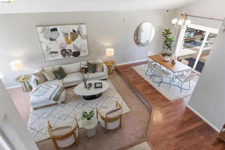Vaulted ceilings enhance this living and dining area, featuring a multi-level wood-finish flooring design and a sliding glass door
