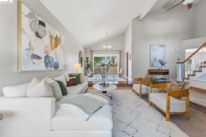 Vaulted ceilings enhance the bright living area, featuring light-toned walls and wood-finish flooring