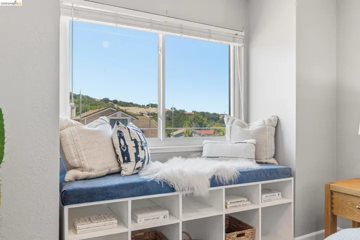 Window seat with built-in storage featuring a blue cushion and open shelving