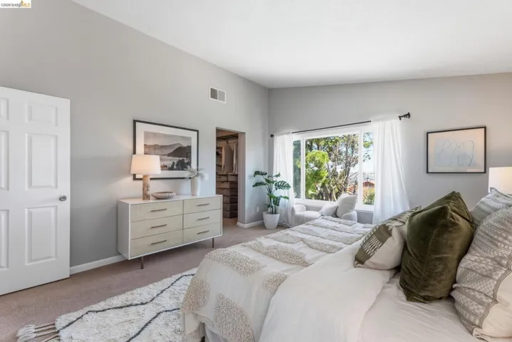 Spacious bedroom with vaulted ceilings and a large window offering ample natural light