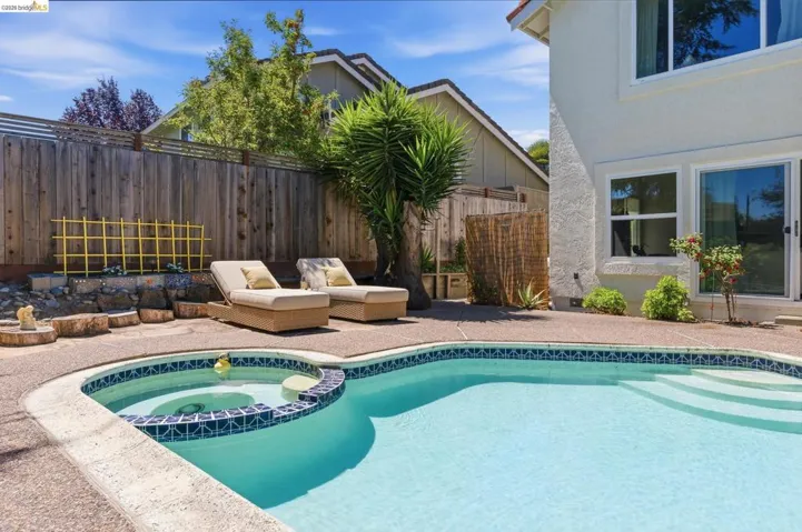 Outdoor pool with integrated spa and surrounding aggregate concrete decking