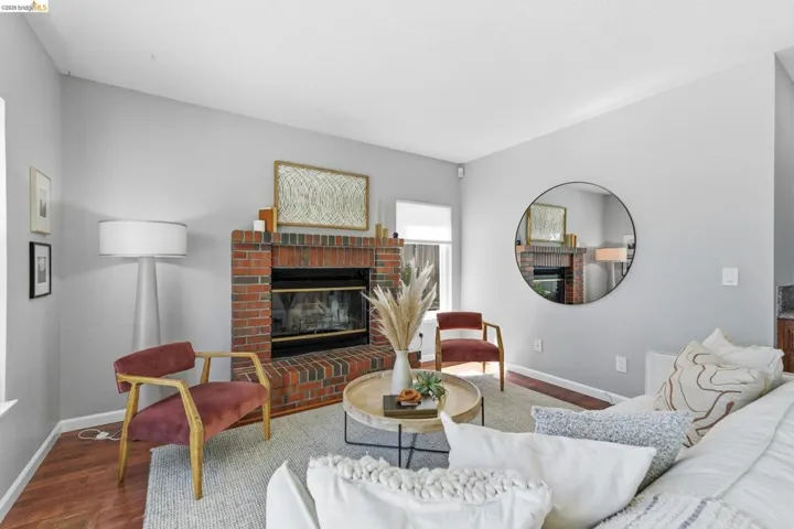 Brick fireplace with black firebox, wood-finish flooring, light grey wall paint, and white trim