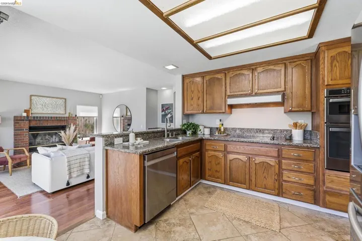 Kitchen featuring wood cabinetry, stainless steel appliances, and stone-finish countertops