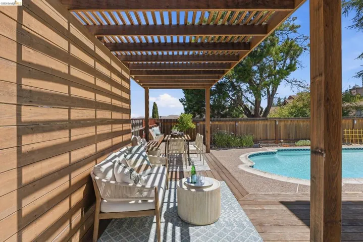 Expansive outdoor living area featuring a wood pergola and a curved swimming pool