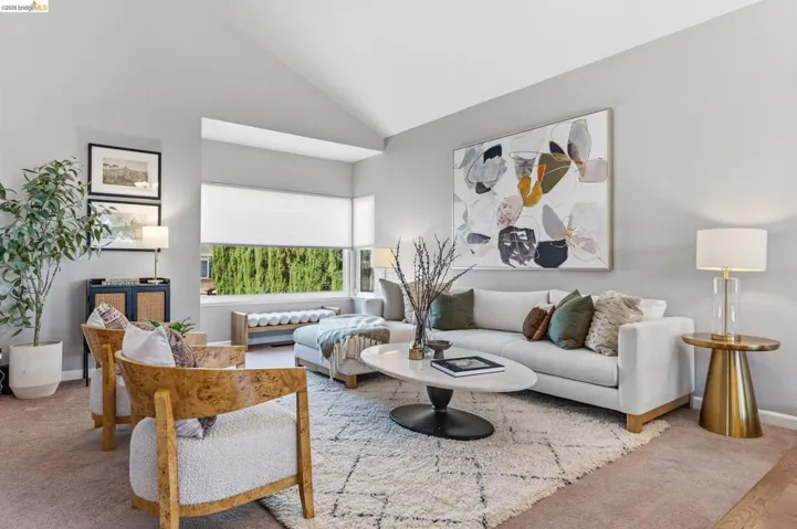 Spacious living area featuring a vaulted ceiling and an expansive window with roller shades