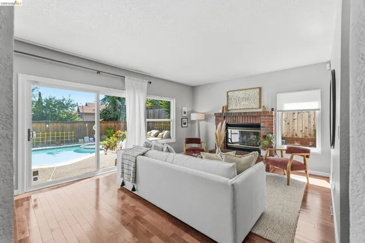 Living area featuring wood-finish flooring, a brick fireplace, and direct access to an outdoor swimming pool via sliding glass doors