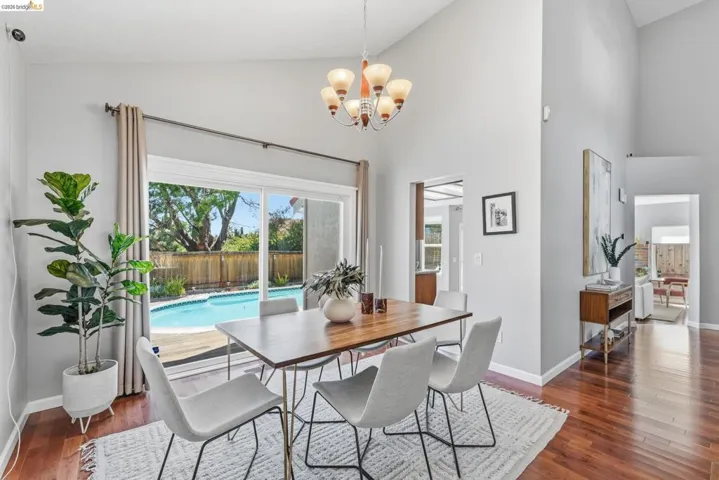 Dining area featuring vaulted ceilings, a contemporary chandelier, and hardwood flooring