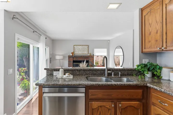 Kitchen featuring granite countertops, a stainless steel double basin sink with a high-arc faucet, and wood-finish cabinetry