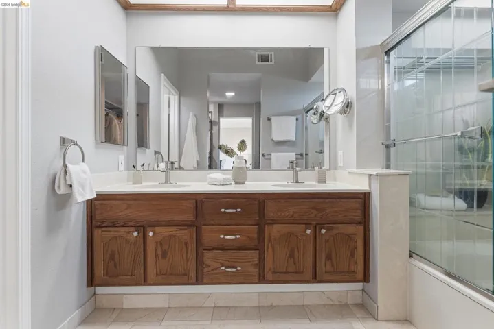 Bathroom featuring a dual vanity with wood cabinetry, light-toned countertop, and undermount sinks