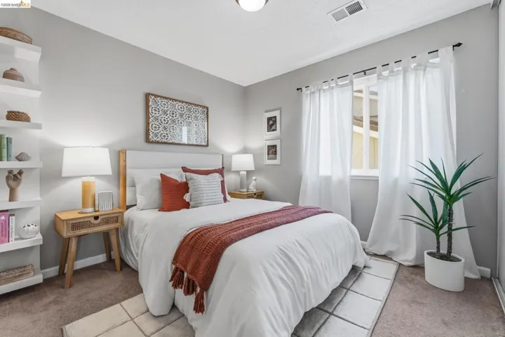 Carpeted bedroom featuring a window with white drapes, a ceiling-mounted light fixture, and built-in shelving