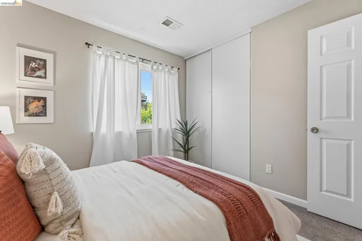 Recessed window providing natural illumination, white panel closet doors, light-colored wall paint, white trim, and gray carpet flooring