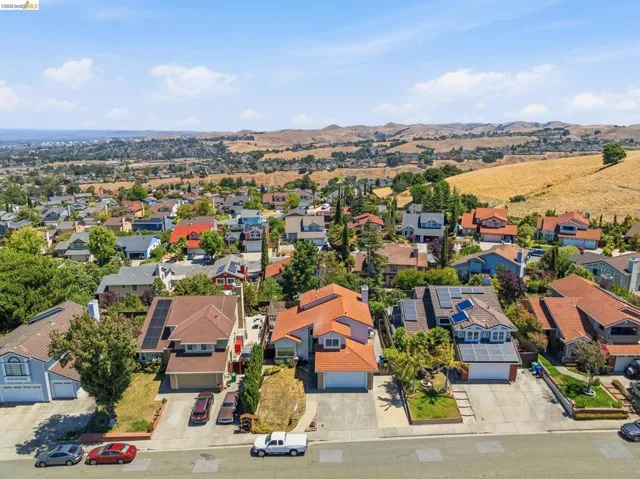 Residential street featuring multiple single-family homes with varying architectural styles, some including rooftop solar panel installations