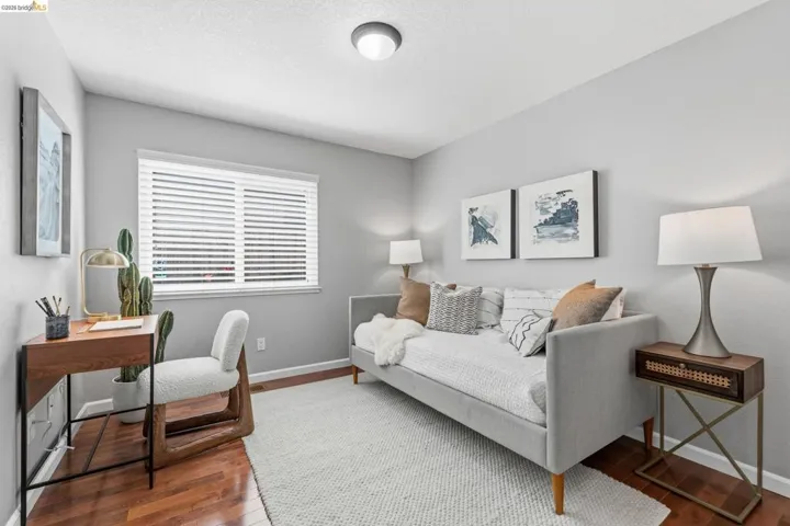 Versatile room featuring wood-finish flooring, a window with horizontal blinds, and a flush-mount ceiling light