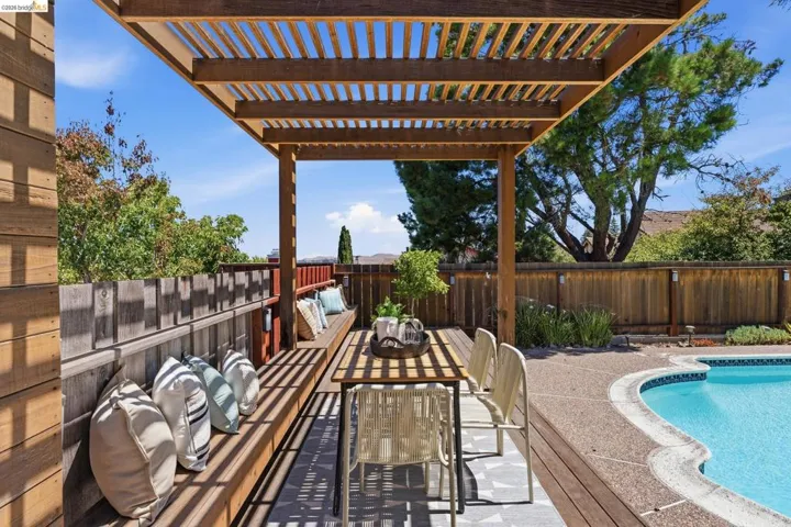 Outdoor living space featuring a wooden pergola, built-in bench seating, a dining area, a freeform swimming pool, and wood decking
