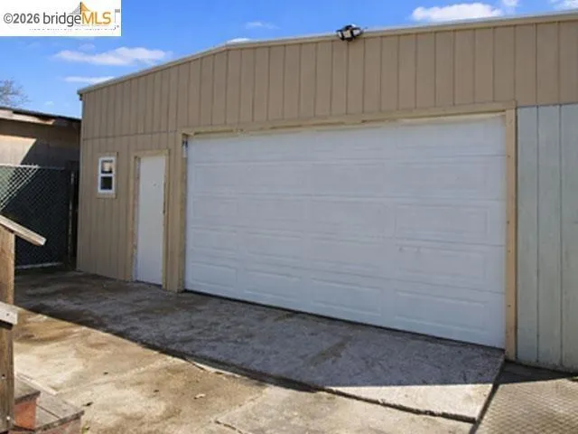 Detached garage featuring a paneled overhead door, a pedestrian access door, and a small window