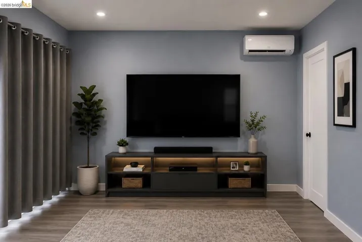Living area featuring wood-finish flooring, recessed ceiling lighting, and a modern wall-mounted climate control unit