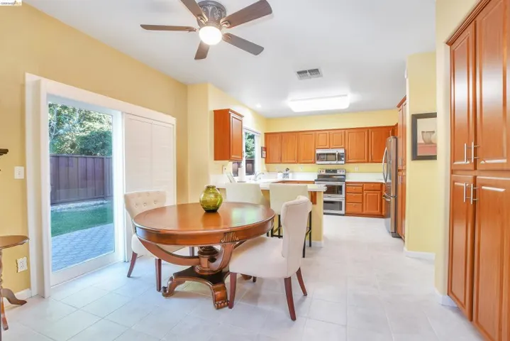 Kitchen with wood-finish cabinetry, stainless steel appliances, and a central island with bar seating