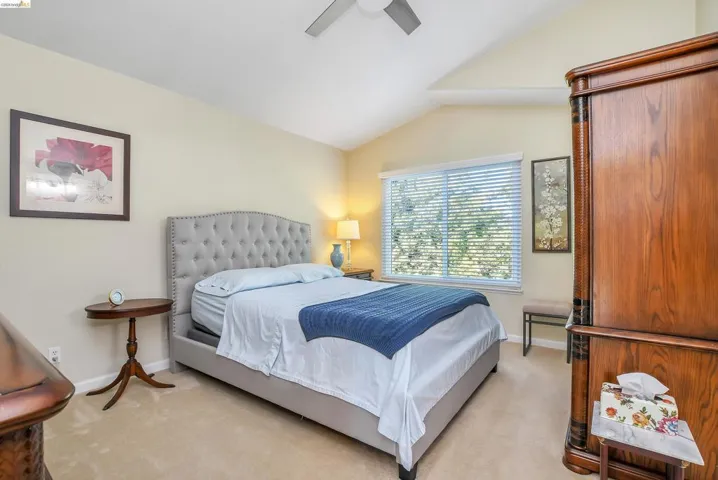 Vaulted ceilings featuring a ceiling fan, window with horizontal blinds, neutral wall paint, and plush carpet flooring
