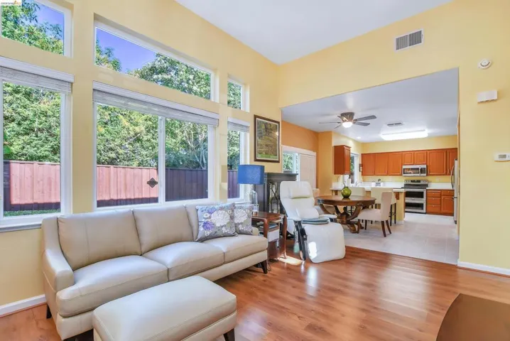 Living area featuring high ceilings, wood-finish flooring, and multiple large windows with transom architectural details