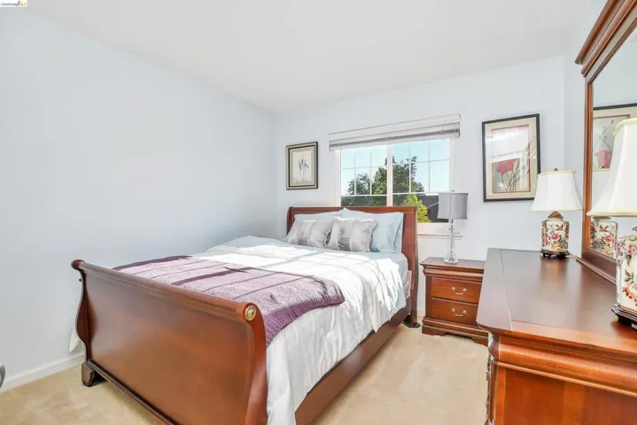 Bright bedroom with light-colored walls and plush carpeting
