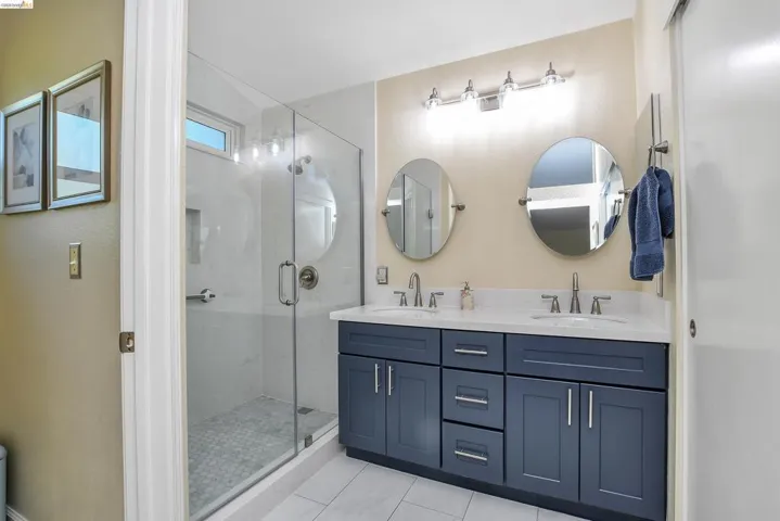 Contemporary bathroom featuring a spacious dual-sink vanity with dark cabinetry and white countertops