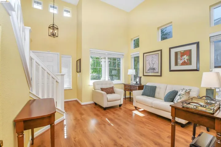 Vaulted entry with a staircase featuring white railings, wood-finish flooring, and multiple windows