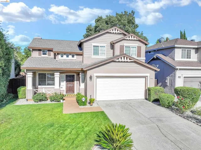 Two-story stucco and siding residence featuring a covered front porch, an attached two-car garage, and a concrete driveway