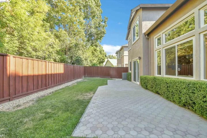 Spacious backyard featuring a large paver patio, a lush lawn, and a tall privacy fence