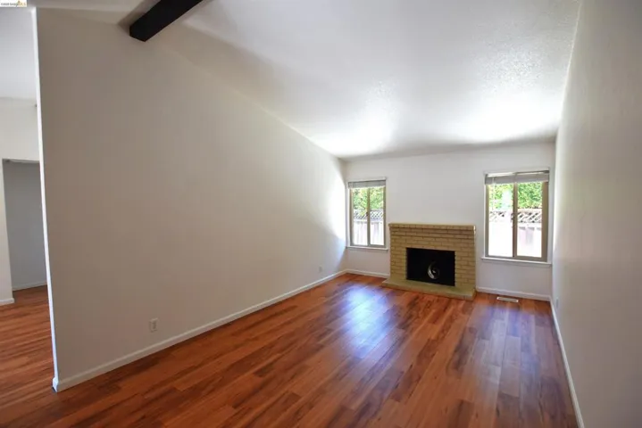 Living area featuring wood-finish flooring, a brick fireplace, and dual windows