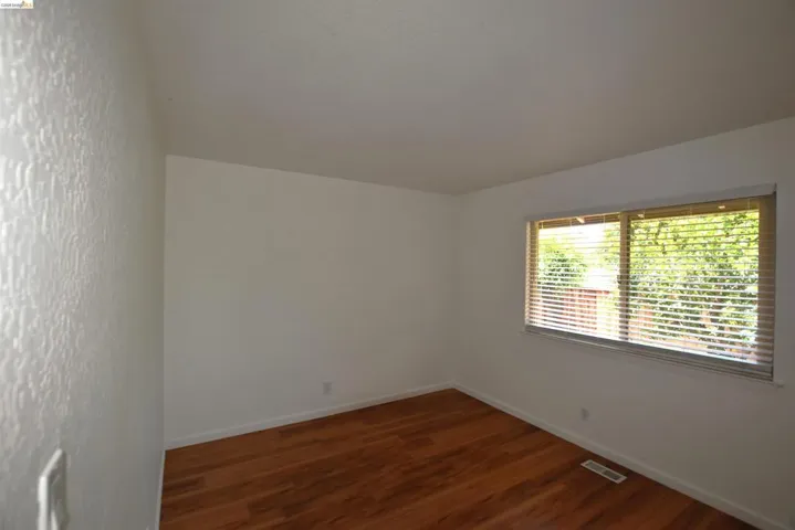 Room featuring wood-finish flooring and a window with blinds