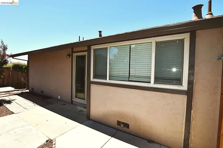 Exterior stucco wall featuring a sliding glass door and a multi-pane window with white frames