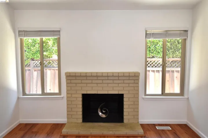 Room featuring a brick fireplace with a black firebox, framed by two windows with blinds