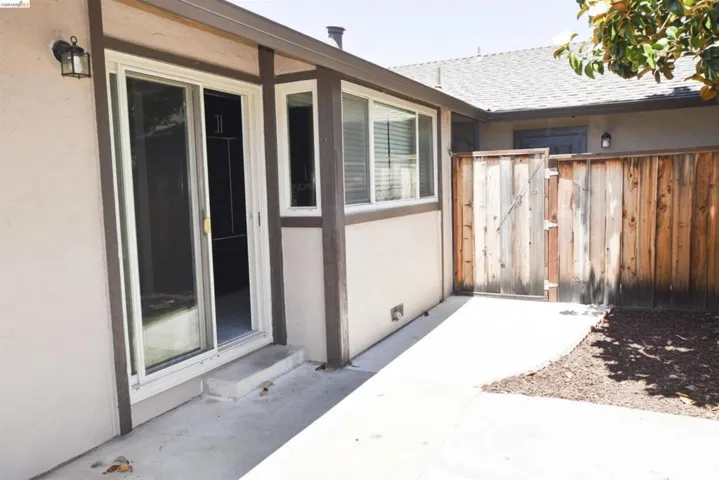 Private outdoor patio space featuring a sliding glass door entry, multiple windows, and a wood privacy fence