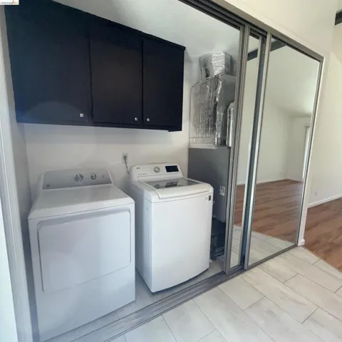 Dedicated laundry area featuring black cabinetry, light-toned tile flooring, and integrated utility access