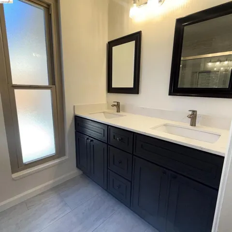 Dual vanity with dark cabinetry, white countertops, and integrated sinks