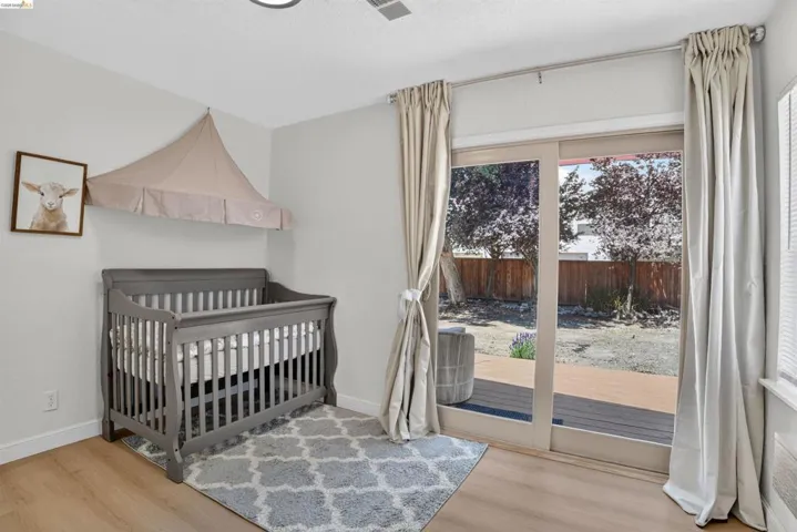 Sliding glass door opening to a private backyard with wood-finish flooring