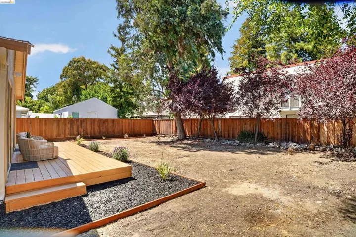 Spacious backyard featuring a multi-level wooden deck, a newly installed wood privacy fence, and mature perimeter trees