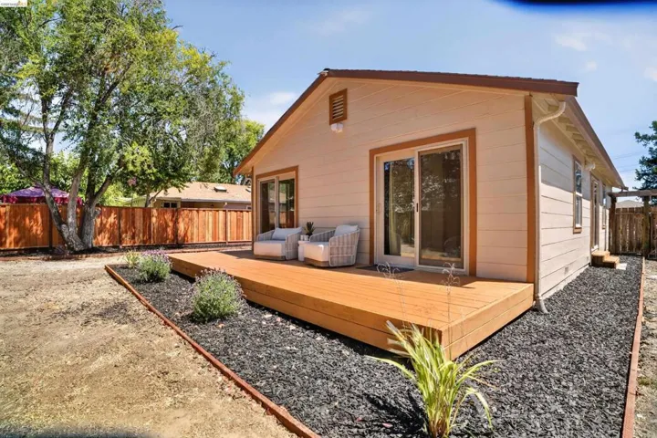 Rear exterior featuring a spacious wood deck, sliding glass doors, horizontal siding, and a wooden perimeter fence