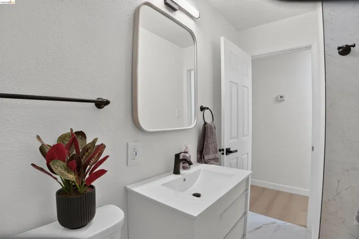 Bathroom featuring a white vanity with integrated sink, black fixtures, and a framed mirror