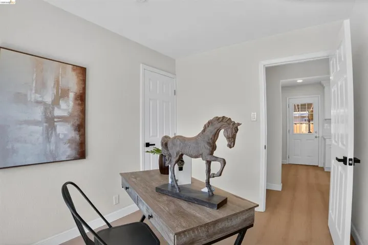 Open doorway revealing wood-finish flooring, white paneled doors with matte black hardware, and light-colored walls
