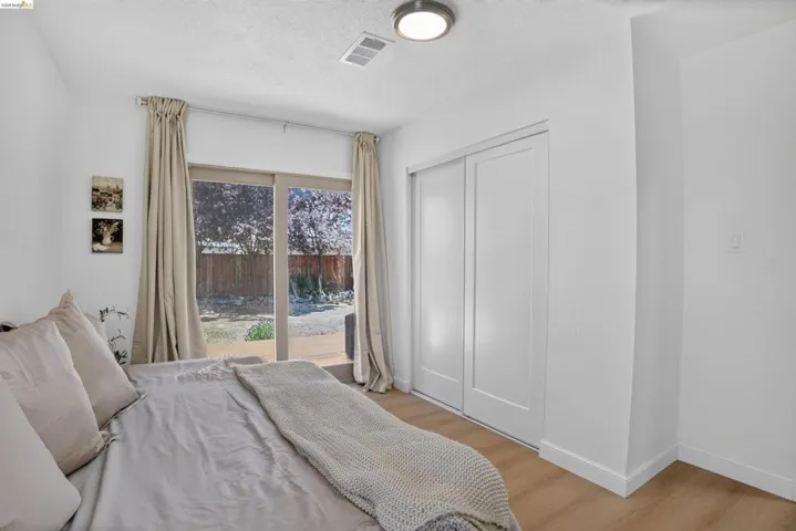 Room featuring sliding glass doors to the exterior, wood-finish flooring, a contemporary ceiling light fixture, and a built-in closet with white bifold doors