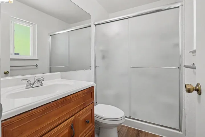 Bathroom featuring a wood-finish vanity with an integrated sink, chrome faucet, and a large mirror