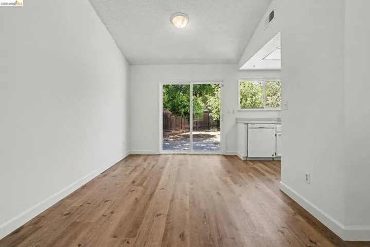 Spacious open-concept room featuring wood-finish flooring, white walls, and a recessed ceiling light